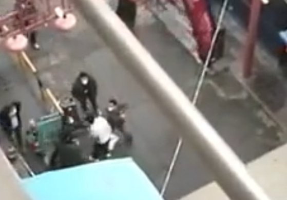 先月３１日、中国西安市のあるアパート団地で黒い身なりの防疫要員の防疫要員が白い身なりの住民を殴打している。［微博　キャプチャー］