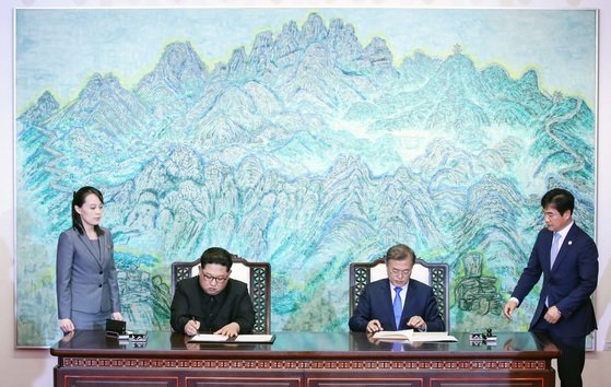 文在寅（ムン・ジェイン）大統領（右から２番目）と北朝鮮の金正恩（キム・ジョンウン）総書記（左から２番目）が２０１８年４月２７日南北首脳会談で韓半島の平和と繁栄、統一のための板門店（パンムンジョム）宣言文に署名している。左側は金総書記の妹・金与正（キム・ヨジョン）労働党第１副部長、右側はチョ・ハンギ当時青瓦台儀典秘書官。［写真　青瓦台写真記者団］