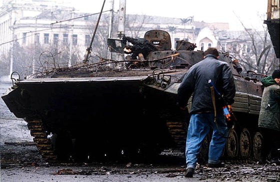 グロズヌイ戦闘当時、チェチェンの戦闘員が破壊されたロシア軍歩兵戦闘装甲車ＢＭＰ－２の前を歩いている。