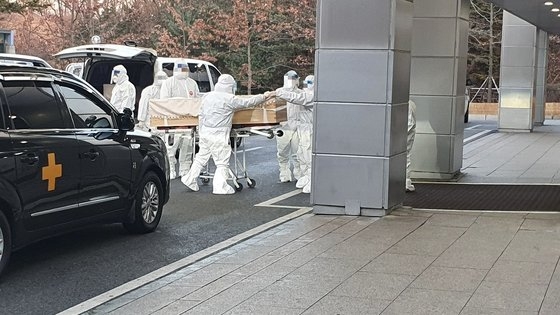 昨年１２月、京畿道の火葬場でレベルＤ防護服を着た職員が新型コロナ感染による死亡者の棺を運んでいる。　［韓国葬儀協会提供］