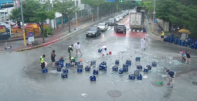 ２９日に江原道春川市のある交差点で左折したトラックからビール瓶２０００本余りが落下し散乱した。これを見た市民が現場を整理している。［写真　春川市］