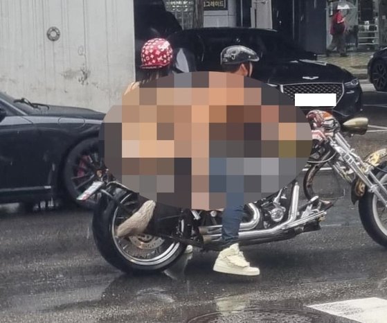 上半身裸の男性がビキニ姿の女性をオートバイの後ろに乗せてソウル市内を走行している様子。［写真　オンライン掲示板　キャプチャー］
