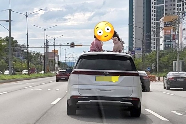 走行中の車のサンルーフから上半身を出す子ども　写真＝オンラインコミュニティ　キャプチャー