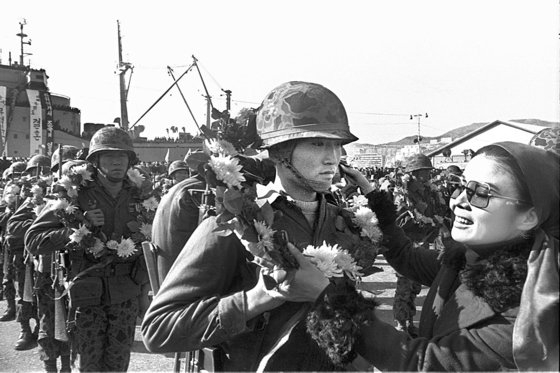 ベトナム戦争から帰還した青龍部隊の隊員が花束を首にかけて家族と対面している。［写真　中央フォトＤＢ］