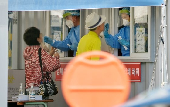 韓国の新型コロナウイルス（新型肺炎）新規感染者が１０万人に肉迫した６日午後、大田（テジョン）ワールドカップ競技場駐車場に用意された新型コロナ選別診療所を訪れた市民がＰＣＲ検査を受けている。［写真　フリーランサー　キム・ソンテ］