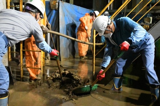 ポスコグループの崔正友会長（右）が１７日に浸水被害を受けた浦項製鉄所の圧延地域地下で社員らとともに土砂を除去している。［写真　ポスコ］