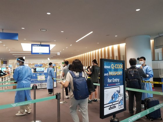 海外から航空便で仁川空港に到着した乗客たちが防疫服を着た職員の案内で入国検疫手続きを踏んでいる。パク・ヒョニョン特派員