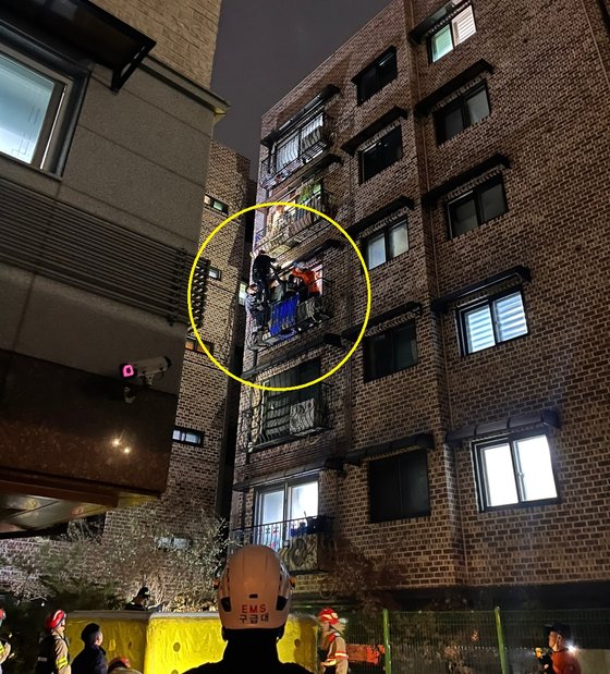 ９日午後、ソウル・東大門区にあるマンションのベランダにぶら下がる高齢女性を警察と消防が救助している。［写真　読者提供］