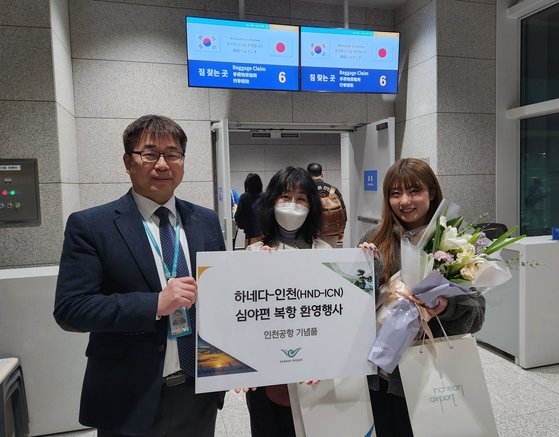 ２７日に運航が再開された大韓航空の羽田～仁川便で入国した日本人観光客が歓迎の花束を受け取っている。［写真　仁川国際空港公社］