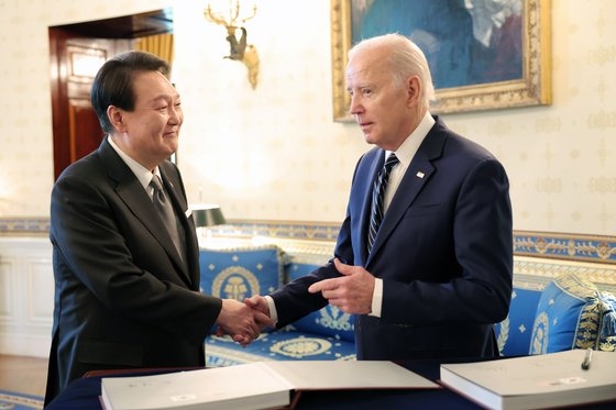 米国を国賓訪問中の尹錫悦（ユン・ソクヨル）大統領が２５日午後（現地時間）、ホワイトハウスで開かれた親交行事で「同盟７０周年写真集」に署名した後、バイデン大統領と握手している。　［韓国大統領室］