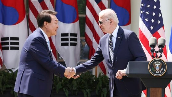 尹錫悦大統領とバイデン米大統領が２６日（現地時間）、少人数会合を終えてホワイトハウスのローズガーデンで共同記者会見を行う前に握手している。　［写真　韓国大統領室写真記者団］