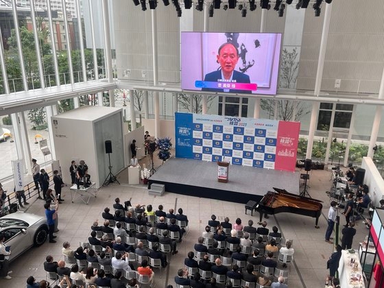 横浜市役所１階ホールで１４日に「Ｙｏｋｏｈａｍａ　ｔｏ　Ｋｏｒｅａ　つながる韓国　２０２３」の開会式が開かれた。写真は日韓議員連盟会長である菅義偉前首相によるビデオメッセージを参加者が聞いている様子。［写真　駐横浜韓国総領事館］
