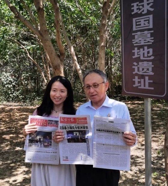 ４日、北京通州の琉球国墓地で玉城デニー沖縄県知事が環球時報の記者と自分のインタビューが掲載された新聞を持ってポーズを取っている。［写真　ツイッター　キャプチャー］