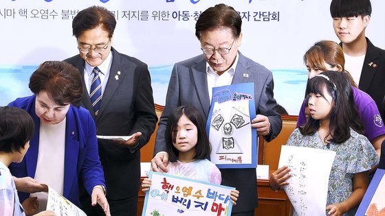 「共に民主党」の李在明代表と議員が８日に国会で開かれた「福島汚染水海洋投棄阻止に向けた児童・青少年・保護者懇談会」出席者らと記念撮影している。キム・ヒョンドン記者