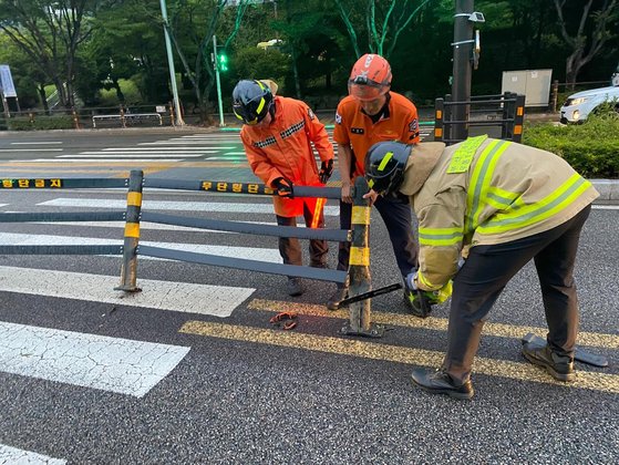 台風６号の影響圏に入った釜山で９日午後、道路に設置された鉄製欄干が破損し消防隊員が措置を取っている。［写真　釜山消防災害安全本部］