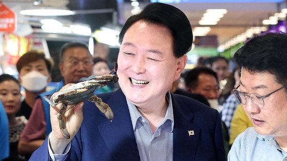 尹錫悦大統領が３１日、ソウル永登浦区（ヨンドゥンポグ）鷺梁津水産物卸売市場を訪れ、ワタリガニを持ち上げて笑っている。［写真　大統領室］