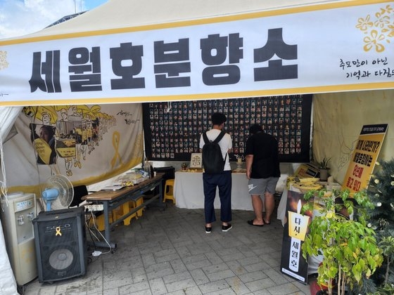 全羅北道全州市殿洞（チョルラブクド・チョンジュシ・チョンドン）の豊南門（プンナンムン）広場に設置されたセウォル号焼香所で、観光客２人が犠牲者を追悼している。［写真　キム・ジュンヒ記者］