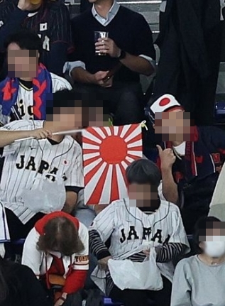 旭日旗を持って応援する日本の野球ファンら。［写真　ニュース１］