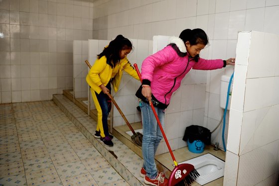 子どもたちが中国の旧式トイレを清掃する姿。［写真　ユニセフ］