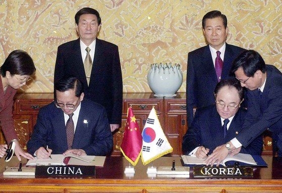 韓国の金大中（キム・デジュン）当時大統領（後列右）と中国の朱鎔基当時首相（後列左）が見守る中、２００２年１０月１８日、両国外相が韓国大統領府である青瓦台（チョンワデ）で条約署名をしている。［写真　青瓦台共同取材団］