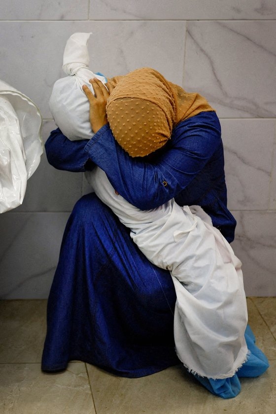 イスラエルの空爆で死亡した姪の遺体を抱いているパレスチナ人女性［写真　ロイター＝聯合ニュース］
