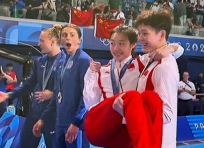  ２０２４年パリ五輪女子シンクロナイズドダイビング３メートル飛板飛込の決勝戦で金メダルを確定した中国代表チームの陳芸文が昌雅妮を持ち上げた。銀メダルを取った米国のキャシディー・クック（左から２番目）がこの姿を見てびっくりしている。［Ｘ　キャプチャー］