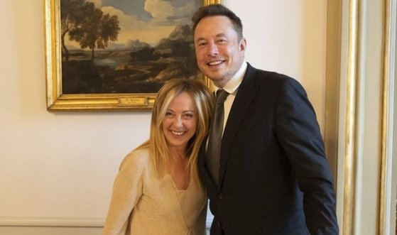 ２０２３年１０月、イタリア首相官邸を訪問したテスラのイーロン・マスク会長がジョルジャ・メローニ首相と抱擁する姿。［写真　テスラ］