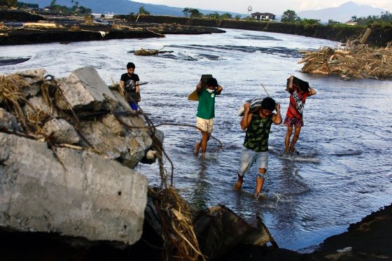 崩落した橋の横で川を渡っているフィリピンのある村の住民［写真　ＥＰＡ＝聯合ニュース］