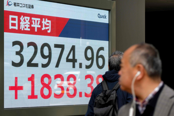 ８日、都内で道行く人々が日本の株価指数を確認している。 ［写真　ＡＦＰ＝聯合ニュース］