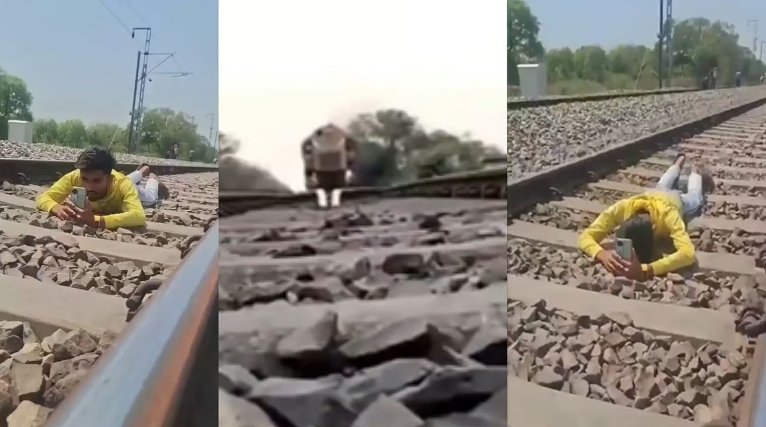 鉄道線路にうつ伏せになって映像を撮影する男性。［写真　Ｘ］  ​