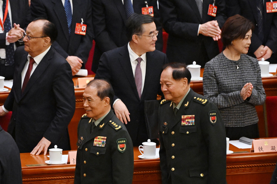 ３月１１日、何衛東中国中央軍事委員会副主席（次席、左）と張友侠中央軍事委副主席（首席、右）が人民大会堂で開かれた全国人民代表者大会の開会式を終えて退場している。何副主席はこの日の行事以降、公開的な席を姿を現さず、粛清説が出ている。　［写真　ＡＦＰ］
