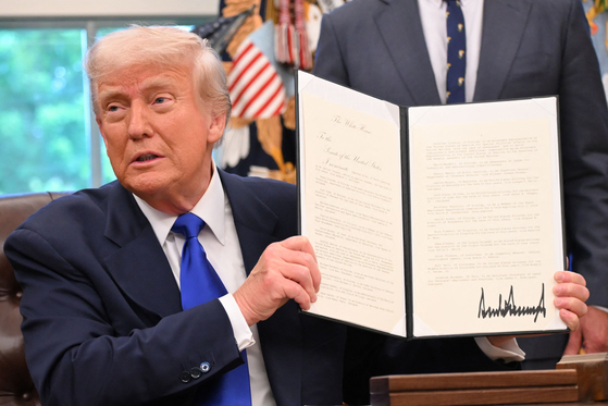 トランプ米大統領が５日（現地時間）、医薬品製造促進に関する行政命令を見せながら記者の質問に答えている。　［ＡＦＰ＝聯合ニュース］