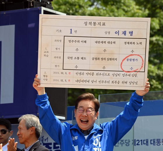 １日、慶尚北道安東市東部洞（キョンサンブクド・アンドンシ・トンブドン）の雄府（ウンブ）公園で開かれた共に民主党の李在明（イ・ジェミョン）大統領選候補の遊説で、小学校の恩師から李候補を評価した仮想の成績表を手渡された候補が明るく笑って成績表を持ち上げている。キム・ソンリョン記者