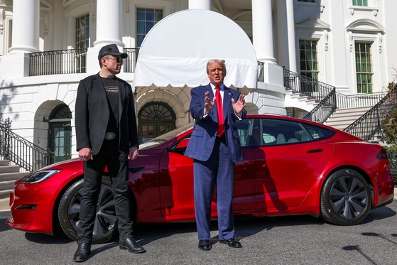 ３月にトランプ米大統領（右）とマスク氏が、トランプ大統領が購入したテスラの車の前でメディアに発言している。［写真　ロイター＝聯合ニュース］