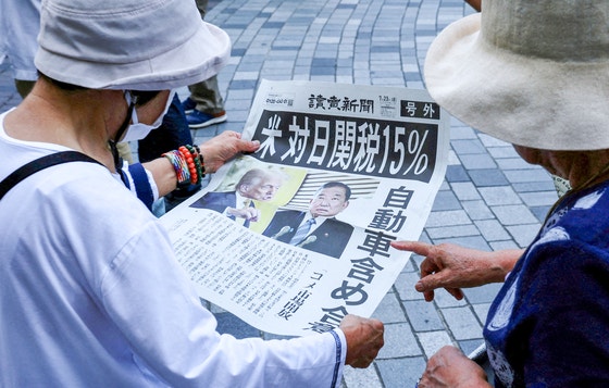 ２３日、東京で市民が「米　対日関税１５％、自動車含め合意」と題された号外を読んでいる。［写真　ロイター＝聯合ニュース］