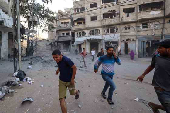 10月19日（現地時間）、イスラエル軍の空爆が行われたパレスチナ難民キャンプ「ブレイジキャンプ」付近で、人々が身を隠している。［AFP＝聯合ニュース］