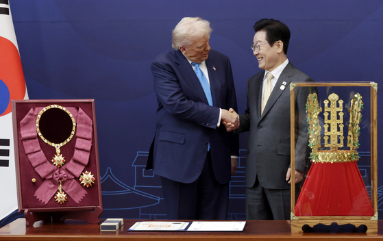 李在明（イ・ジェミョン）大統領が29日、慶州博物館でトランプ米大統領に「天馬塚（チョンマチョン）金冠模型」を贈った後、握手している。左は李大統領がトランプ大統領に授与した無窮花（ムグンファ）大勲章。 ［聯合ニュース］