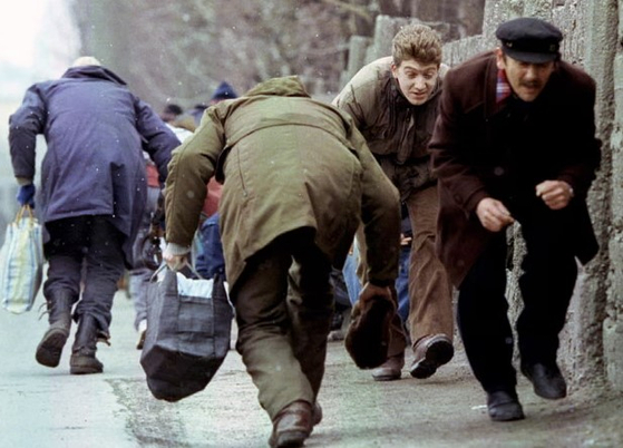 1993年ボスニア内戦当時、セルビア狙撃兵の集中射撃を避けるため身をかがめてサラエボ市内を横切る市民たち。ロイター＝聯合ニュース