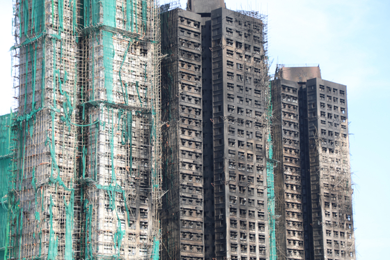 28日（現地時間）、火災が鎮火した香港大埔区の高層マンション群「宏福苑」の窓ガラスが割れたり溶けたりしてなくなっている。 ［聯合ニュース］