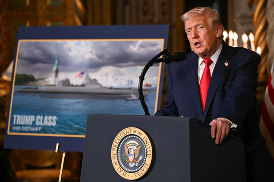 トランプ米大統領が22日（現地時間）、フロリダ州パームビーチのマールアラーゴの私邸で米海軍の「黄金艦隊」構築計画を発表した。トランプ大統領の横に自身の名前が入った「トランプ級戦艦」の想像図が見える。 ［AFP＝聯合ニュース］