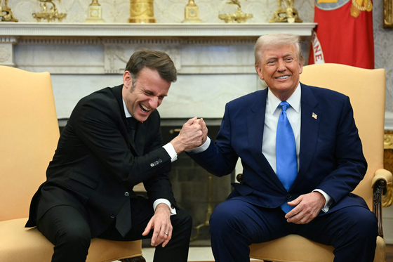 米国のドナルド・トランプ大統領（右）とフランスのエマニュエル・マクロン大統領が昨年2月24日（現地時間）、ホワイトハウスの大統領執務室で互いの手を強く握り締め、握手を交わしている。AFP＝聯合ニュース