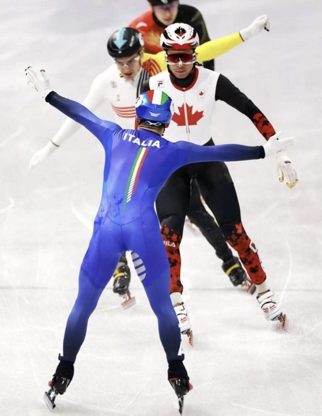   後ろ向きで決勝ラインを通過する伊ショートトラック混合リレー代表選手［写真 X］