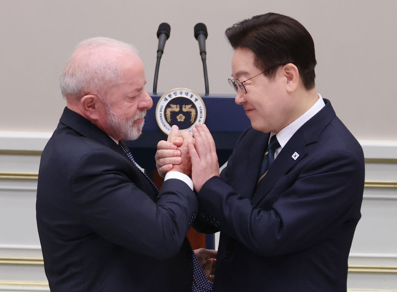 韓国の李在明（イ・ジェミョン）大統領が23日、青瓦台（チョンワデ、大統領府）で開かれたブラジルのルイス・イナシオ・ルーラ・ダ・シルバ大統領の国賓訪韓歓迎晩餐会で、答辞のために移動するルーラ大統領と手を握り合っている。聯合ニュース