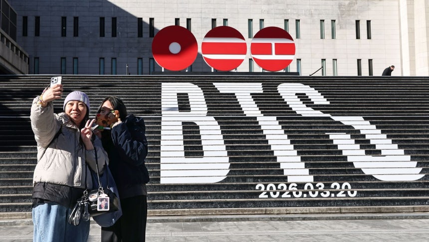 ソウルの世宗文化会館で香港からの観光客が来月3年9カ月ぶりに完全体で復帰するBTSのカムバックを知らせる広報物を記念撮影している。［写真 聯合ニュース］