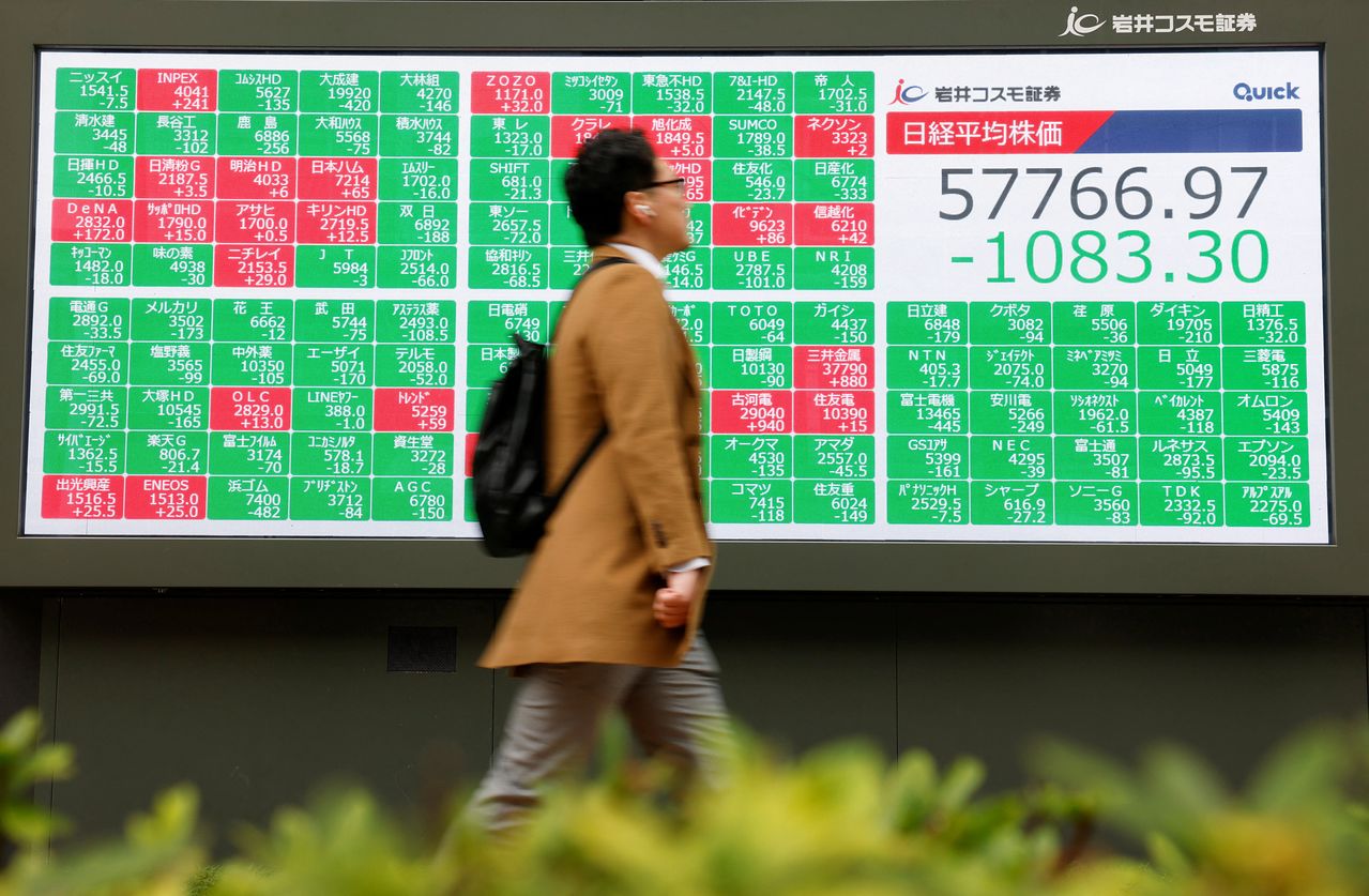  2日、男性が東京の証券会社の株式モニター前を歩いている。［写真 ロイター＝聯合ニュース