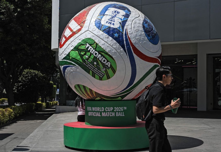 3日にメキシコシティである男性が2026FIFAワールドカップ開幕100日前を記念して展示された公式試合球「トリオンダ」の大型模型のそばを通り過ぎている。［写真 AFP＝聯合ニュース］