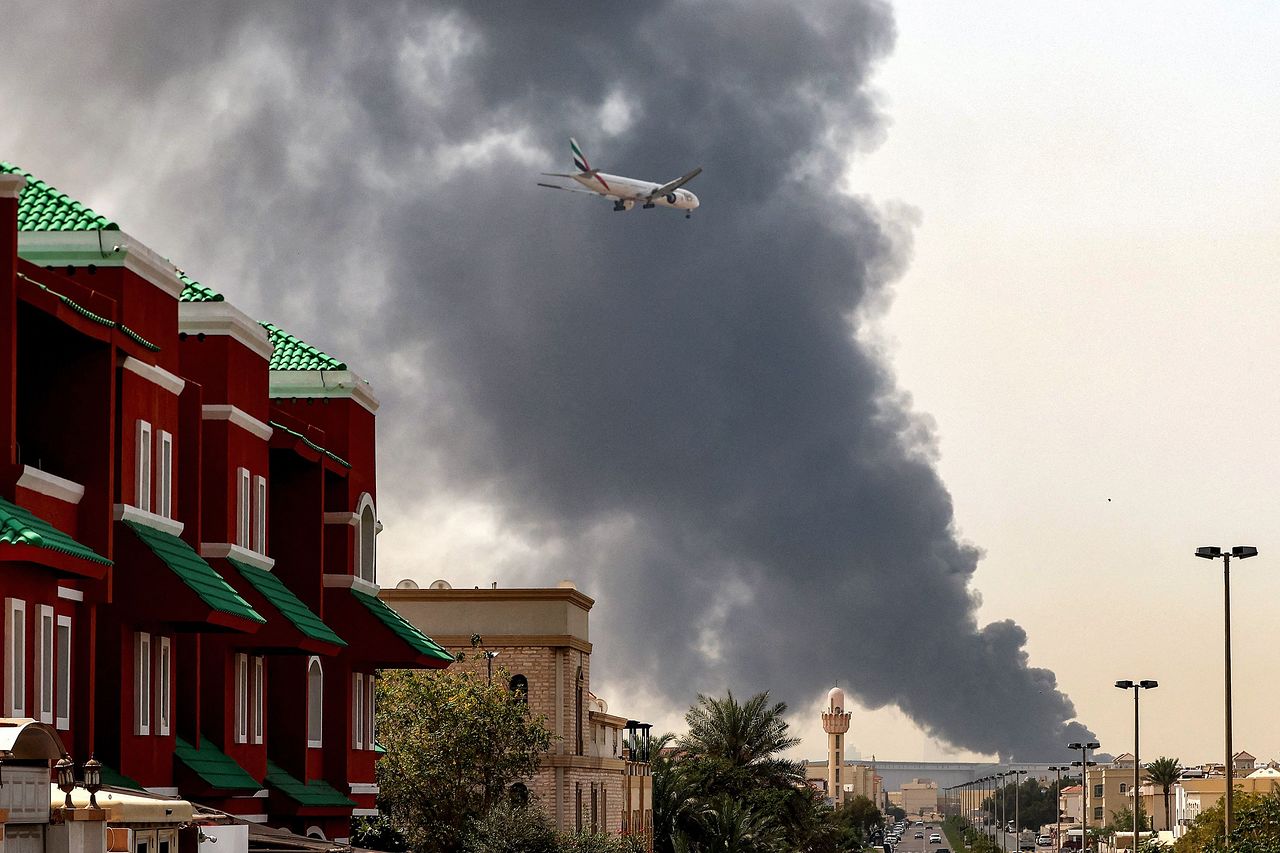 16日、アラブ首長国連邦（UAE）のドバイ国際空港近隣がイランの攻撃による爆発で火炎と煙に包まれる中、エミレーツ航空所属の飛行機が着陸を準備している。AFP＝聯合ニュース