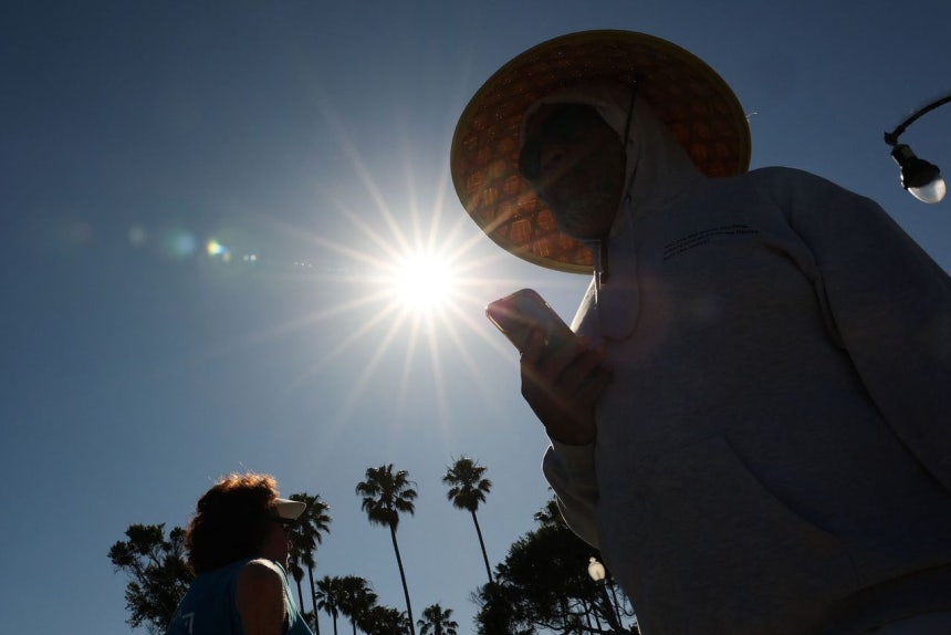 20日（現地時間）、米カリフォルニア州の浜辺で強い日差しの中、帽子をかぶった市民が歩いている。［AFP＝聯合ニュース］