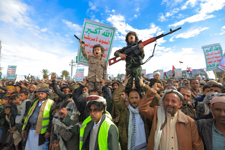 27日、イエメンのサヌアで、反政府武装組織のフーシ派を支持する少年が群衆の上に立ち、拳銃と小銃を手にしてイランおよびレバノンのヒズボラとの連帯を訴え、米国とイスラエルを糾弾するデモを行っている。フーシは28日、イスラエルに向けてミサイルを発射し、米国・イラン戦争勃発後初めて軍事行動に乗り出した。［AFP＝聯合ニュース］