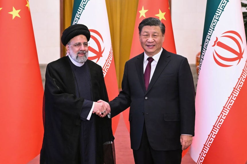 2023年2月、北京を訪問したイランのエブラヒム・ライシ大統領（左）が中国の習近平国家主席（右）との会談に先立ち握手している。中国は米国とイランの戦争でイランが敗北しないよう支援していると専門家は分析する。AP＝聯合ニュース
